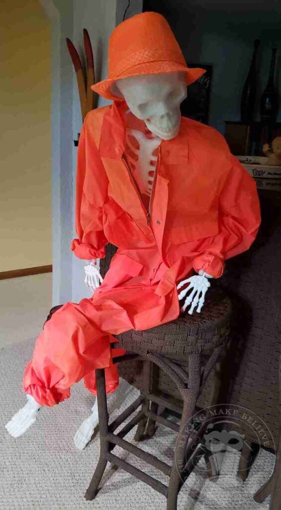 Skeleton prop dressed in orange attire and place on a bar stool