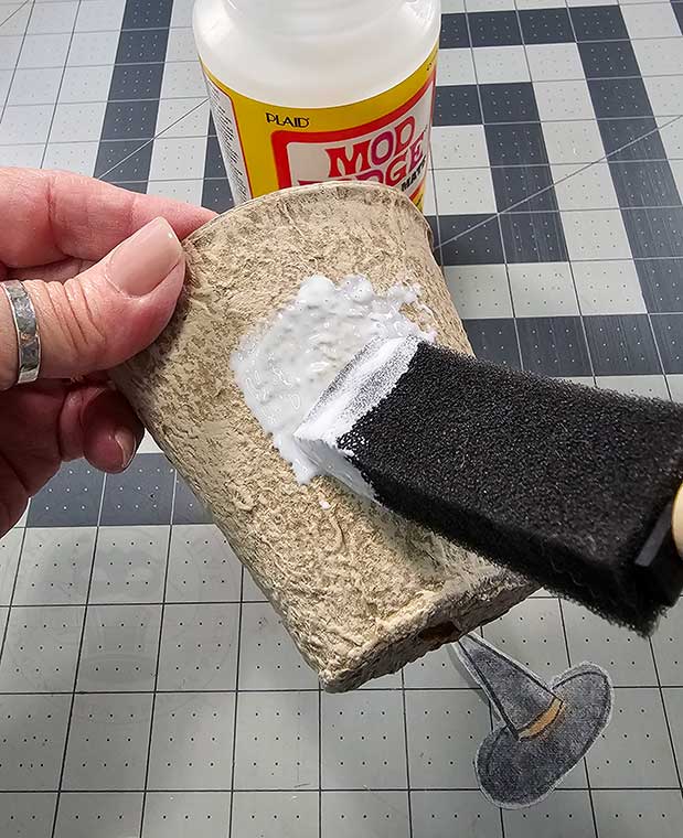 Brush Mod Podge onto section of pot