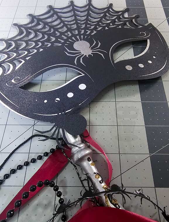 Venetian mask stick decorated with ribbons and attached to masquerade mask