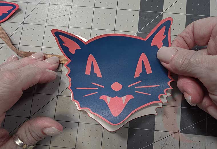 Align cat face pieces sandwiching ribbon in between